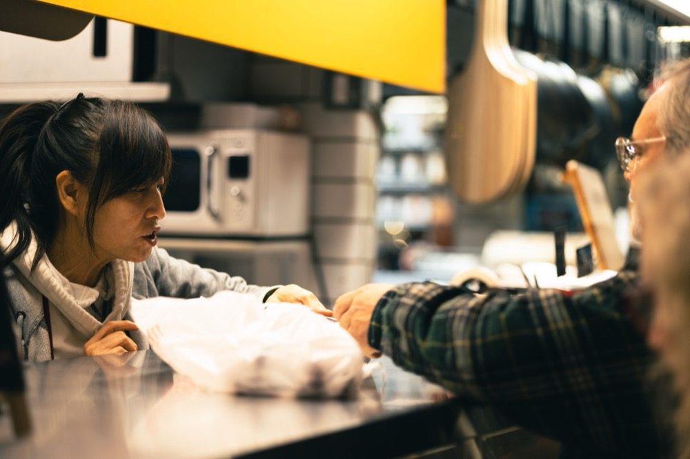 A local vendor handing a product to a customer across a market counter