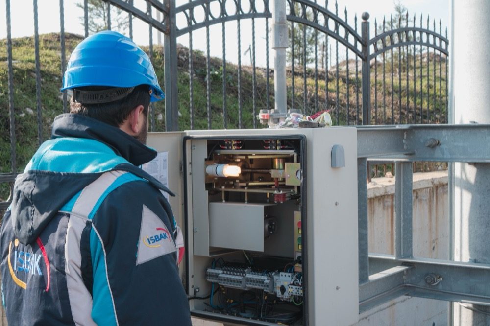 An electrician in a hard hat inspecting a fuse box