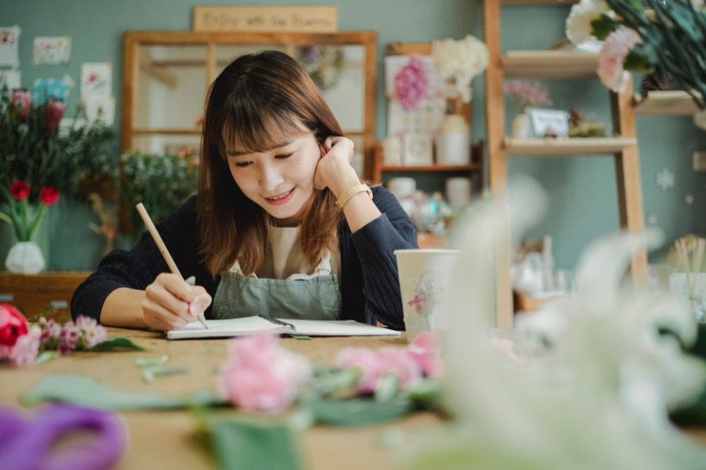 A florist writing notes at the counter of her flower shop