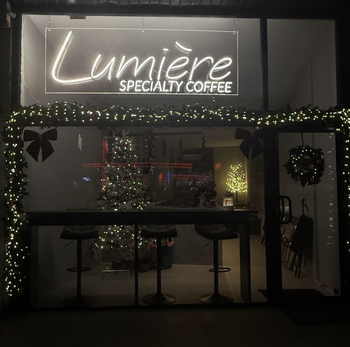 Fațada Lumière Specialty Coffee noaptea cu semnul neon cursiv iluminat